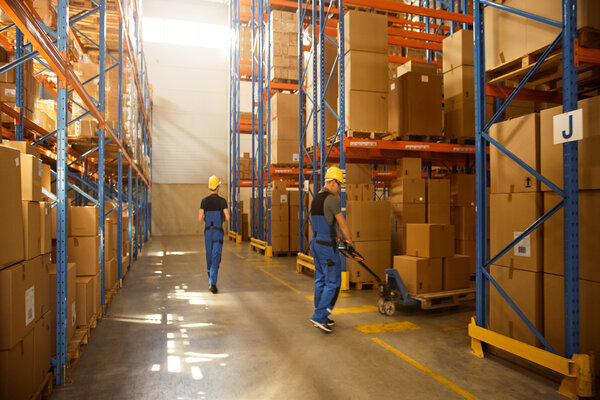 Retail Delivery Warehouse full of Shelves with Goods in Cardboard Boxes, Workers Scan and Sort Packages, Move Inventory with Pallet Trucks and Forklifts. Product Distribution Logistics Center.